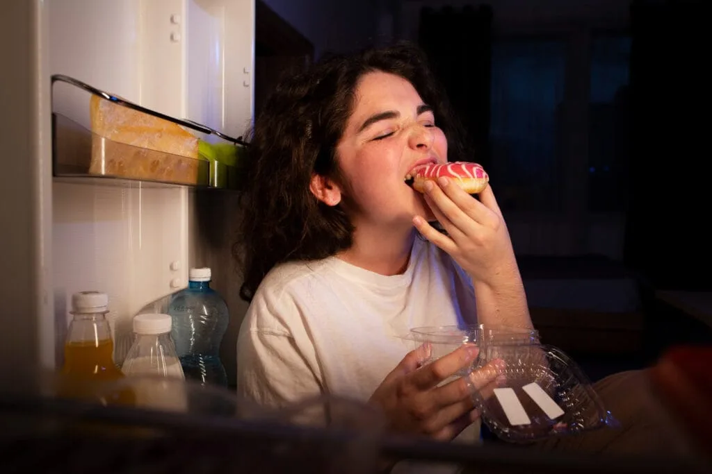 Uma mulher está comendo um donut na cozinha