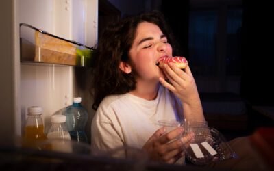 A woman is eating a donut in the kitchen